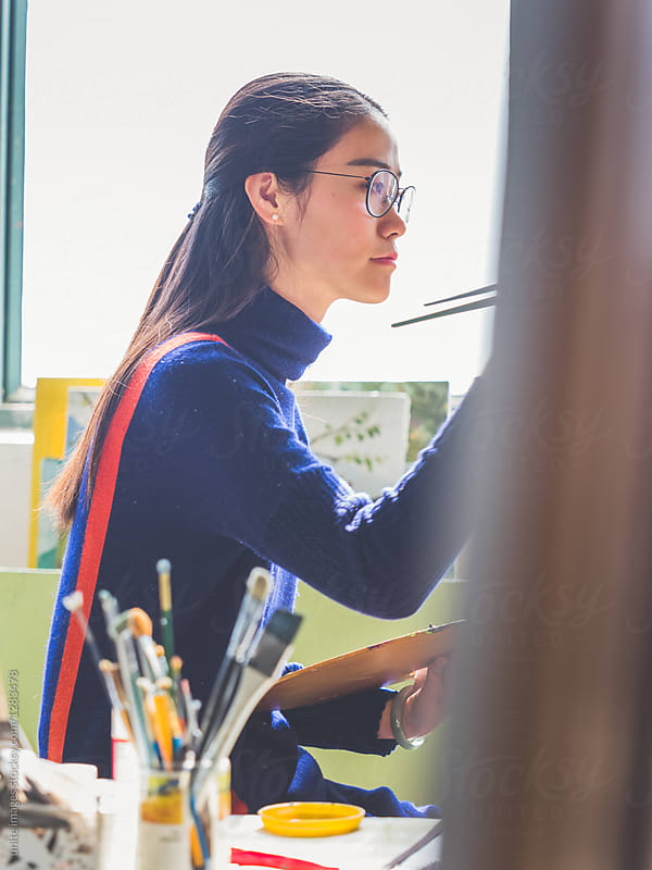 side view of a female artist painting in an art studio of college
