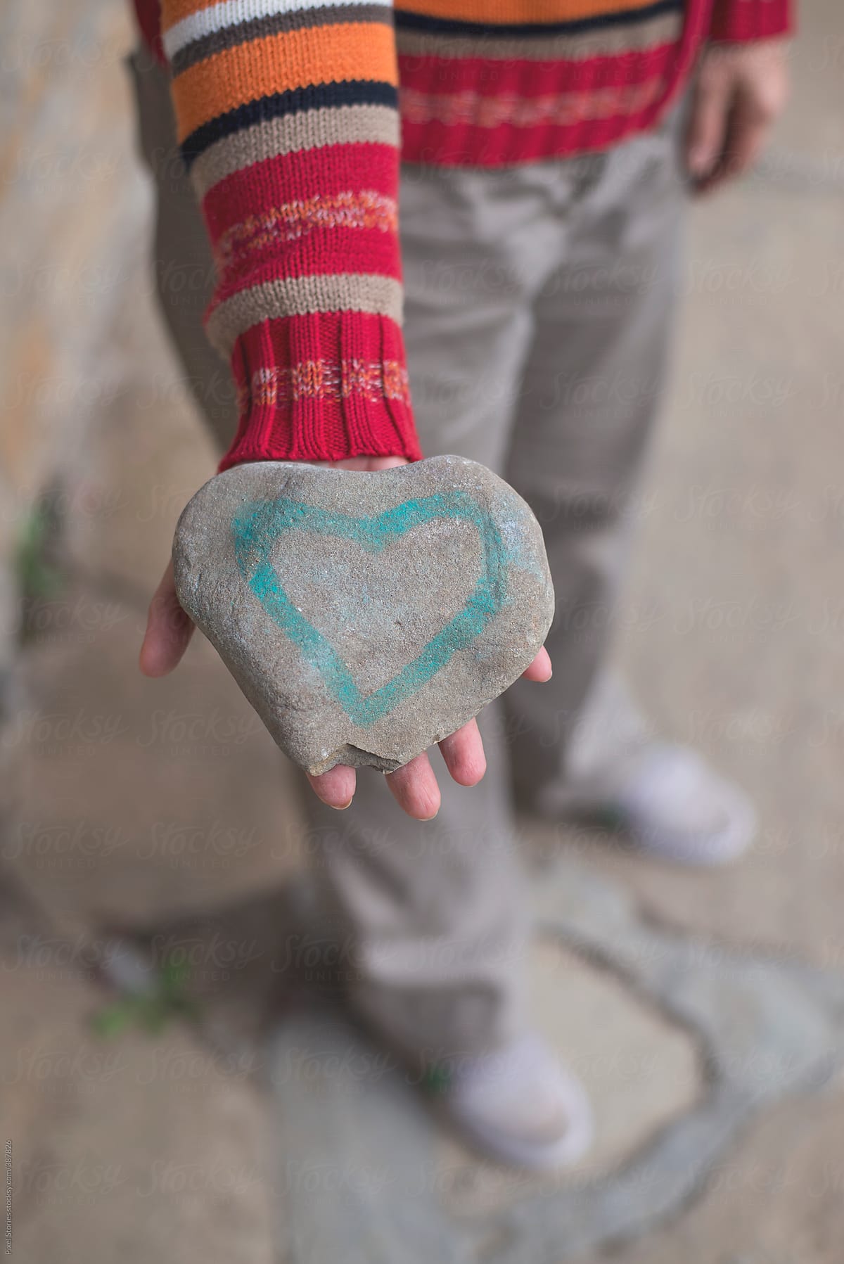 Woman holding heart-shaped stone with painted heart