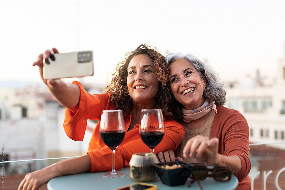 Happy senior women friends taking photo on terrace
