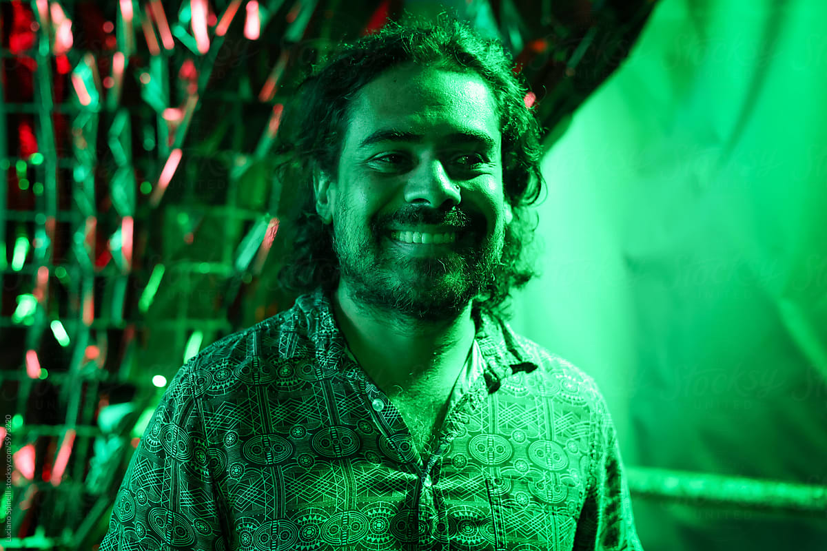 Cool guy enjoying party under green light smiling and looking away