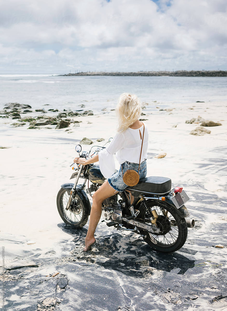 Anonymous woman on motorbike on beach