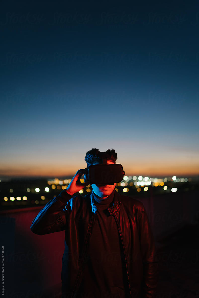 Man in VR helmet on terrace at sunset