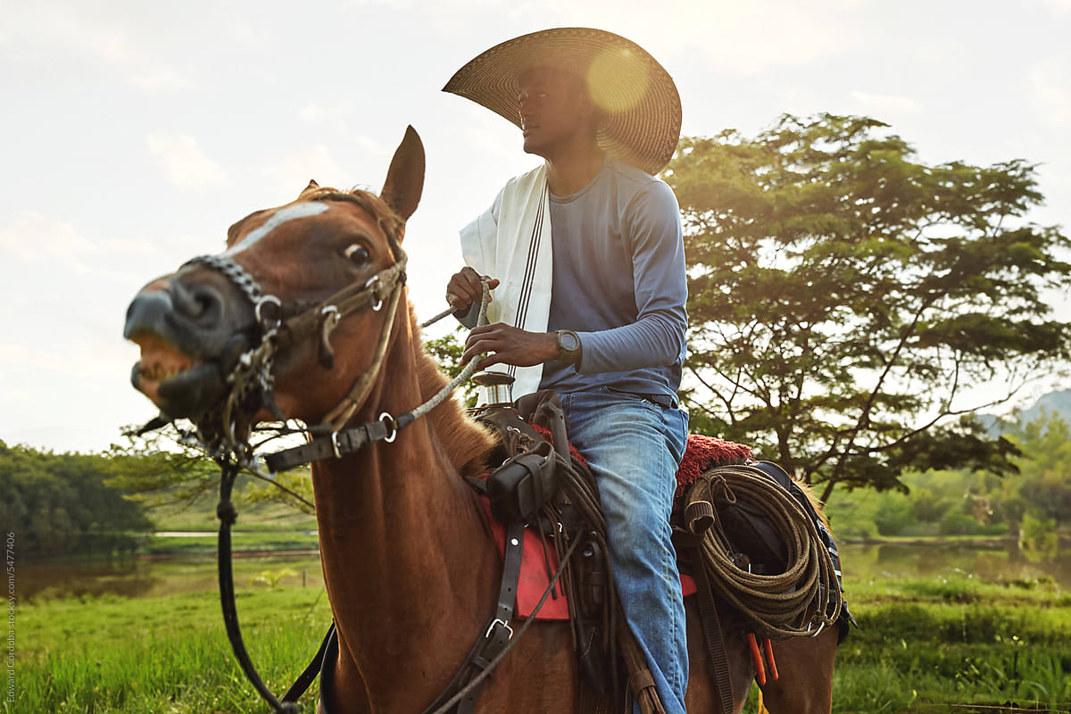 Smiling cowboy portrayed riding on his horse on a Colombian farm
