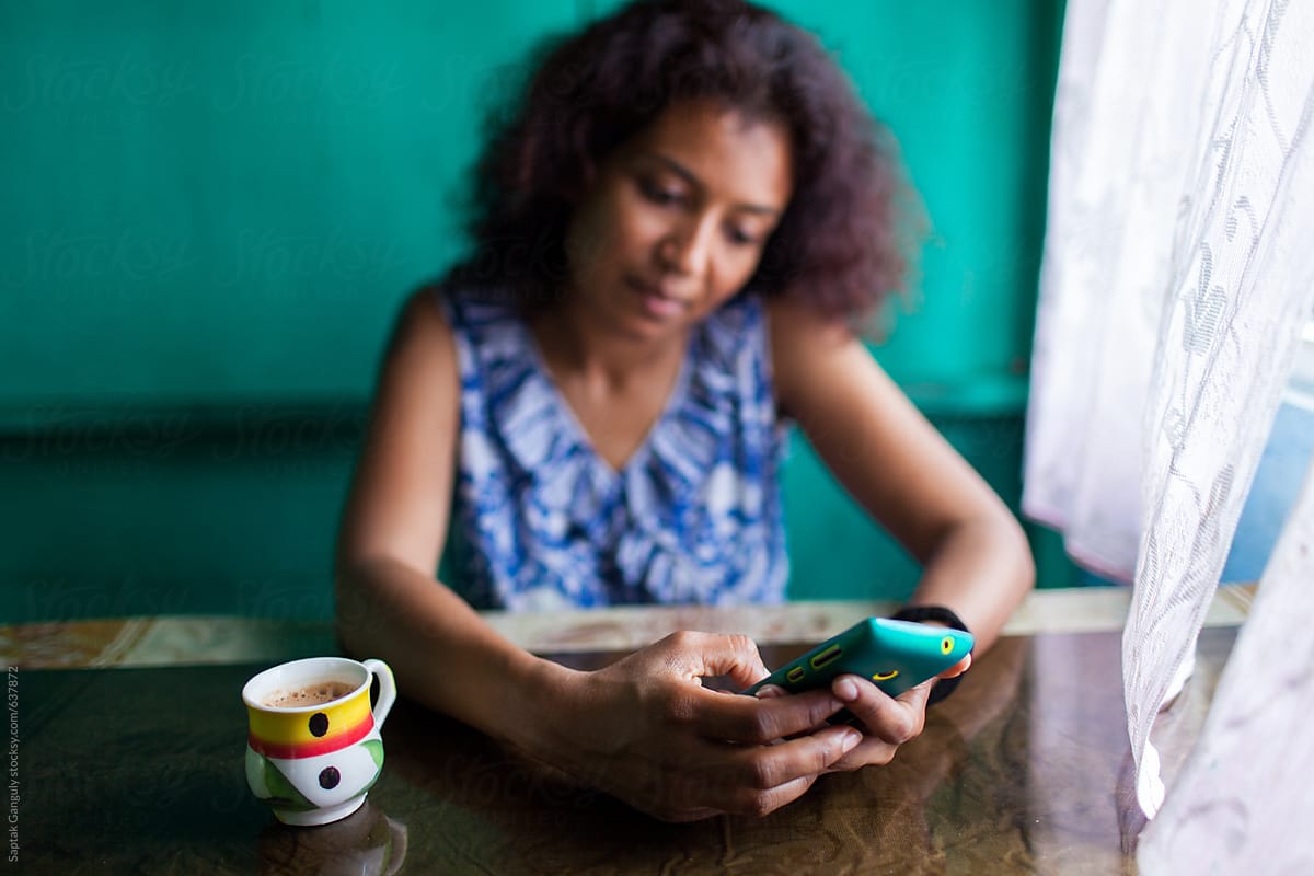 Woman having tea and using her mobile phone inside a rural restaurant