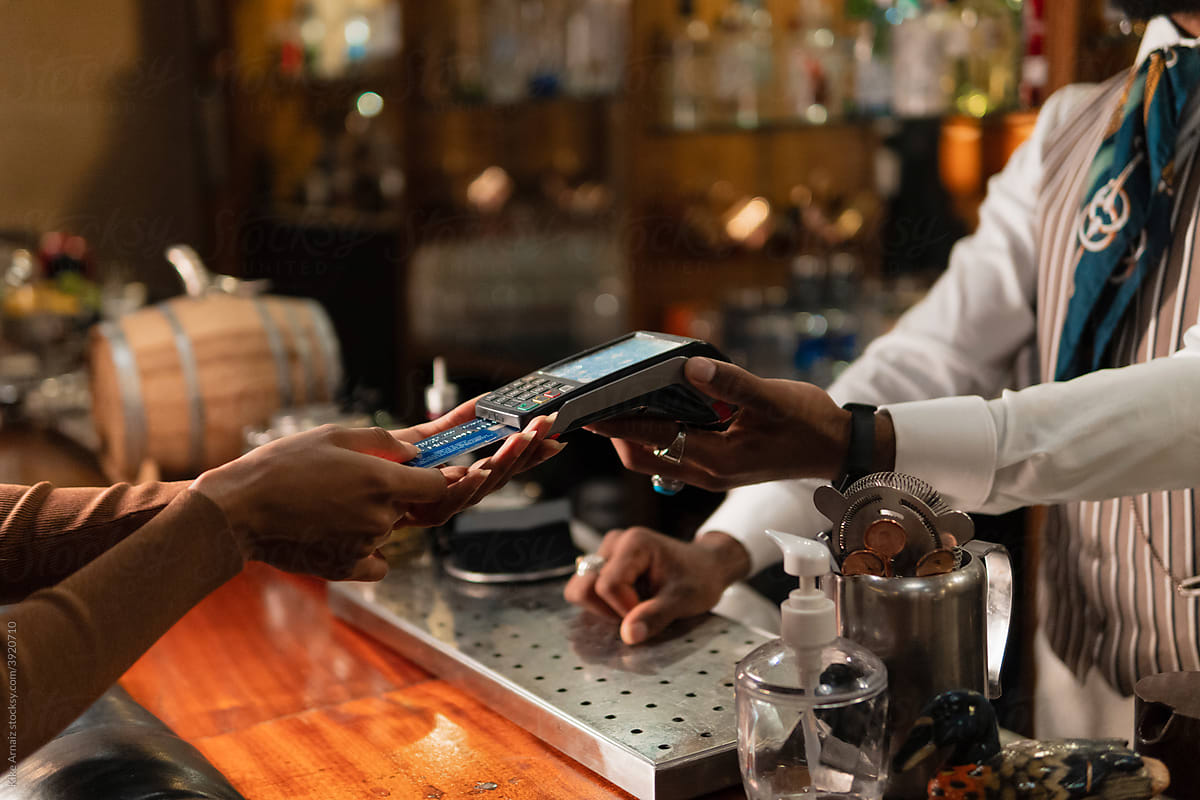 Crop black woman paying for order to barman
