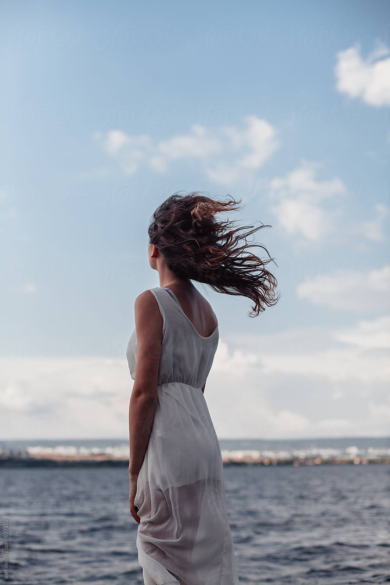 Back of a young woman watching the sea on a windy day
