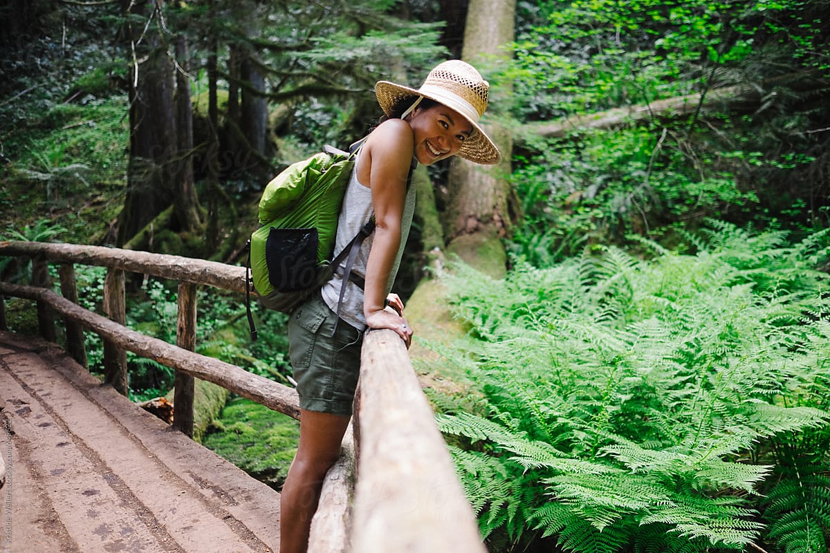 Woman smiling on a bridge while on a hike in the forest