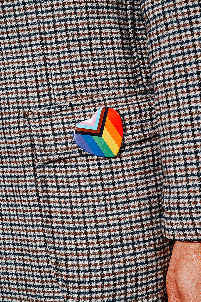 wears a badge with the progress pride flag