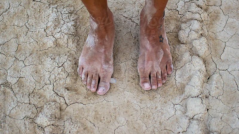 Female barefoot on dry parched ground on the desert