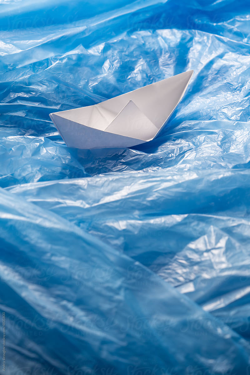 Plastic bags in the ocean. Paper ship swim through the ocean from bags