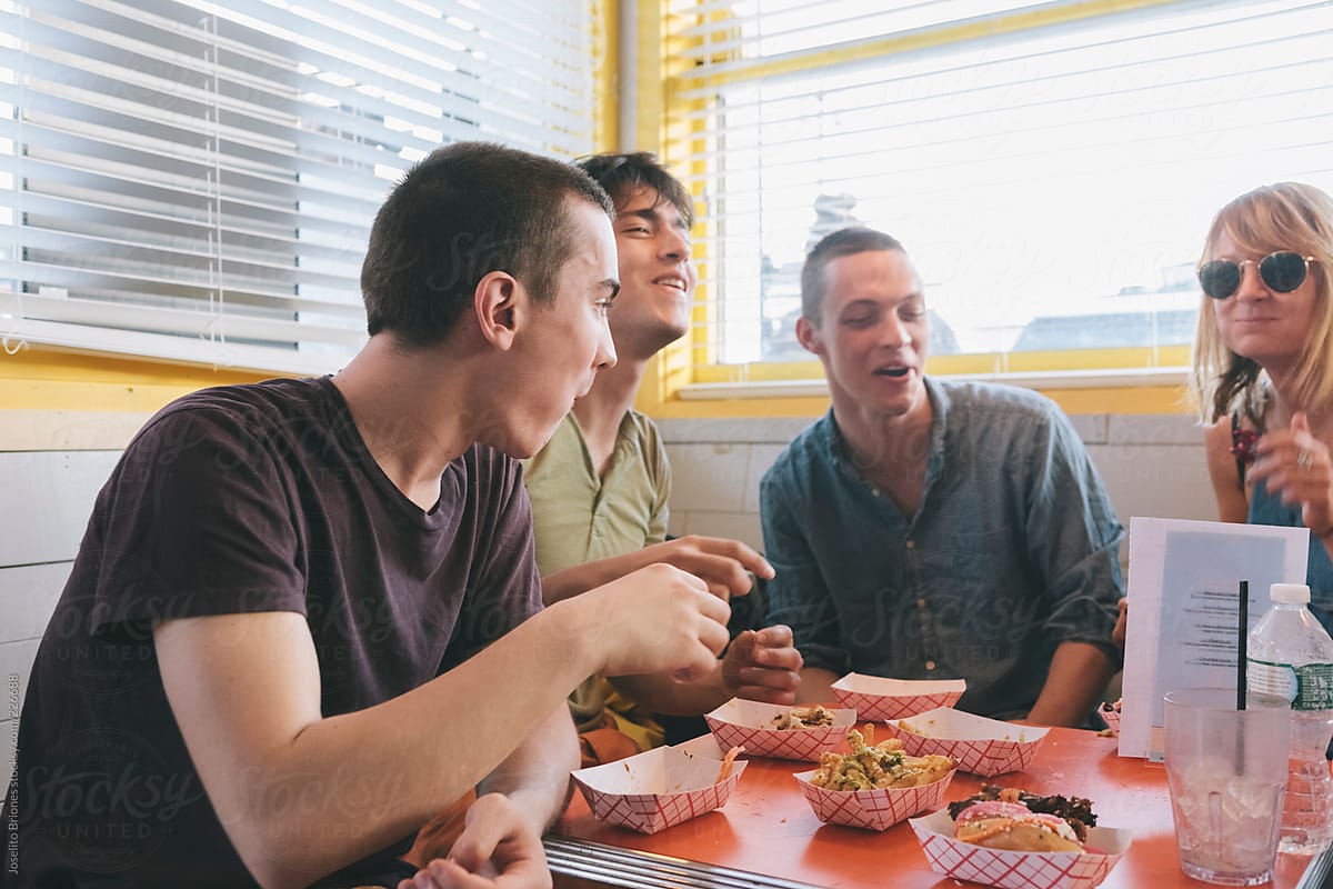 Group of Young Friends Eating Burger Sliders and Fries in a Beach Diner