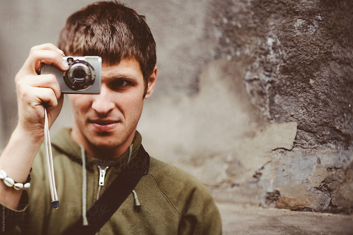 Young man taking a snapshot with compact camera