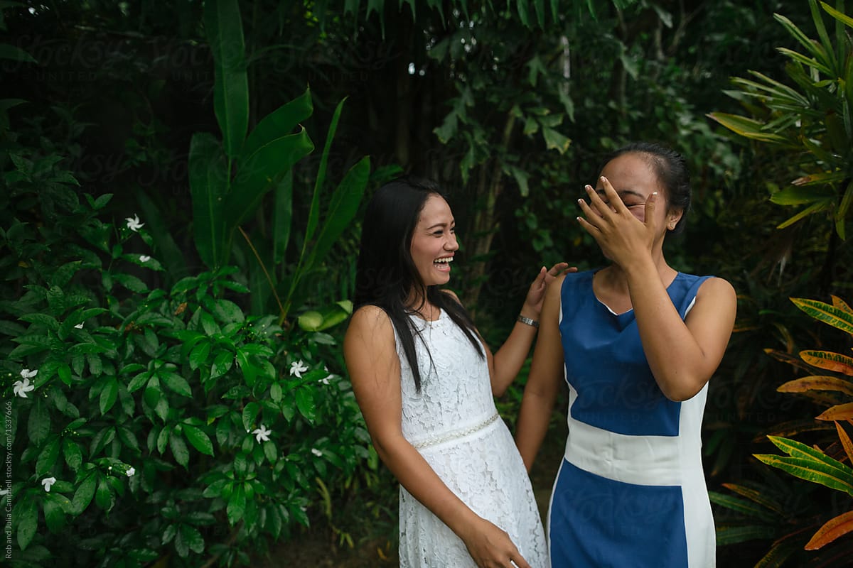 Young balinese women together laughing in nature - embarrassed