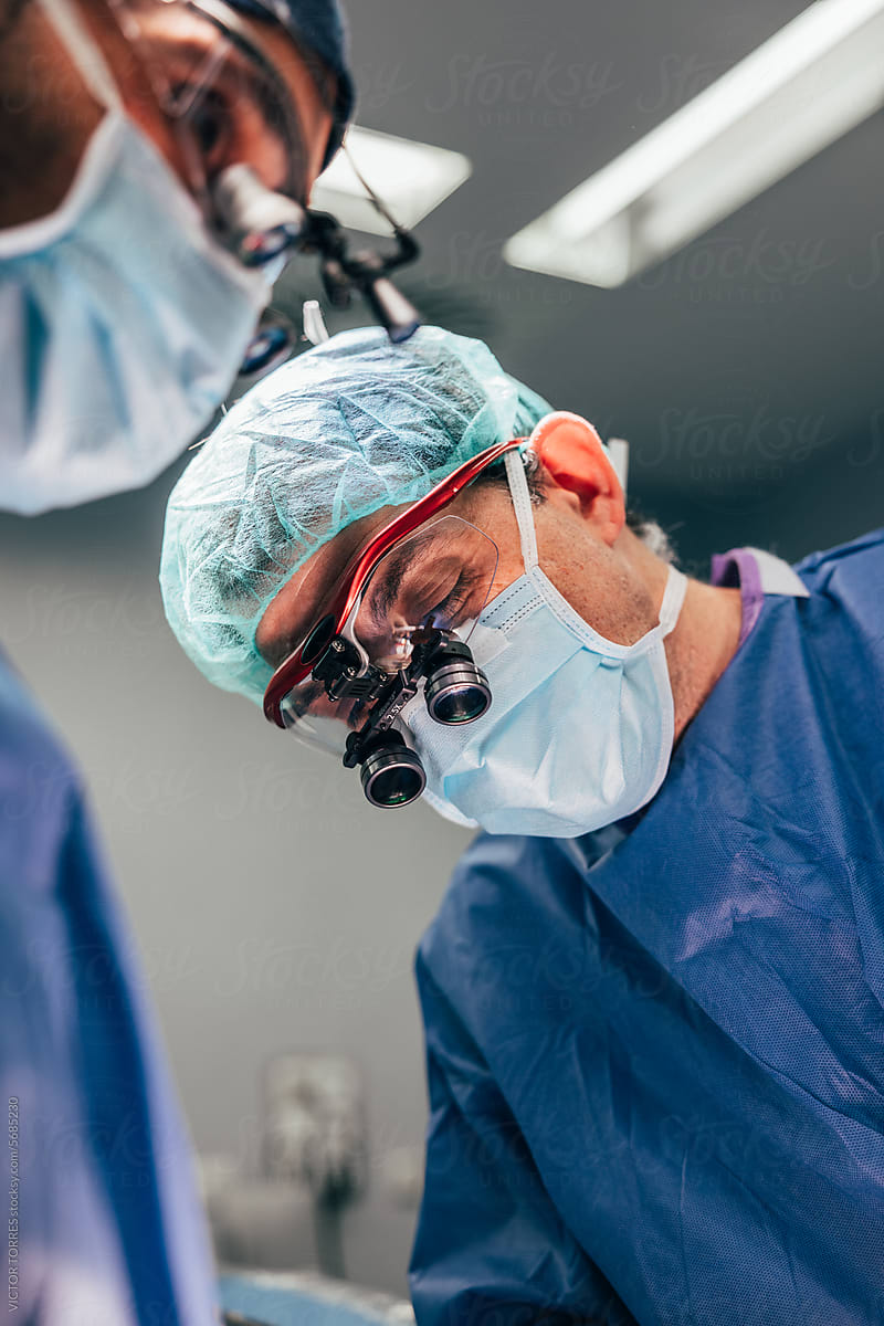 Male doctors performing thyroid surgery in operating room