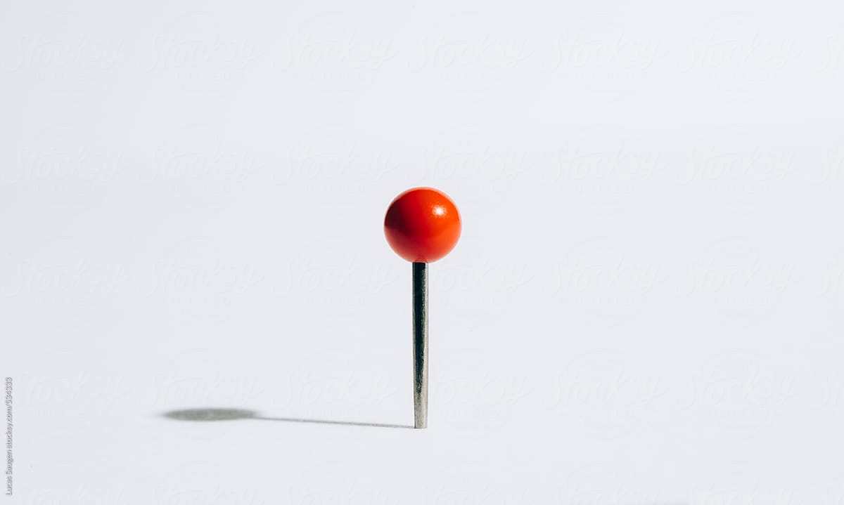 A red push pin casting a shadow.