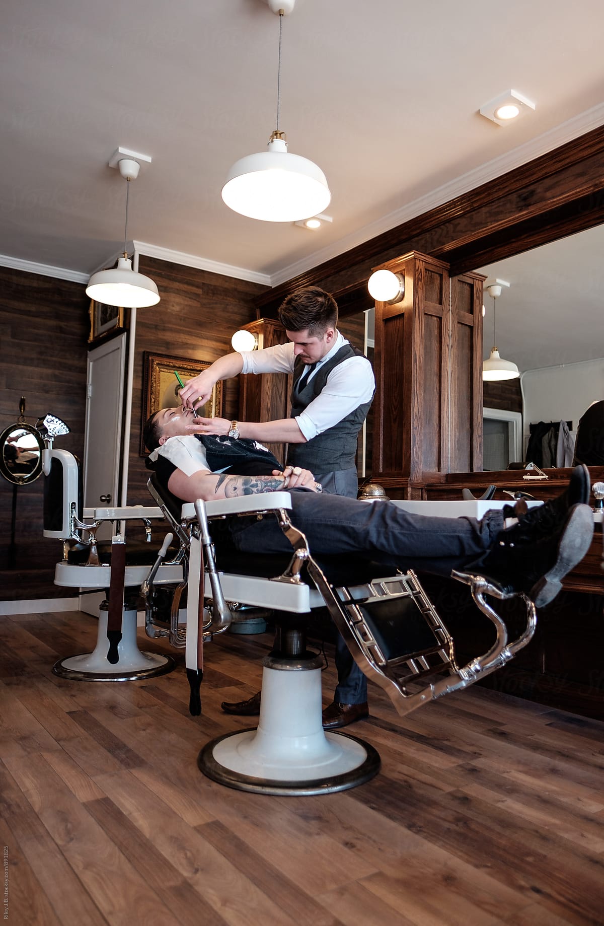 A client reclines in a vintage barber chair while receiving a classic