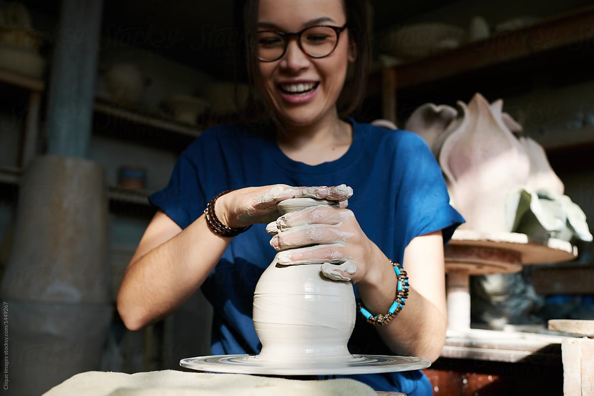 Female potter enjoying work on throwing wheel in local ceramics