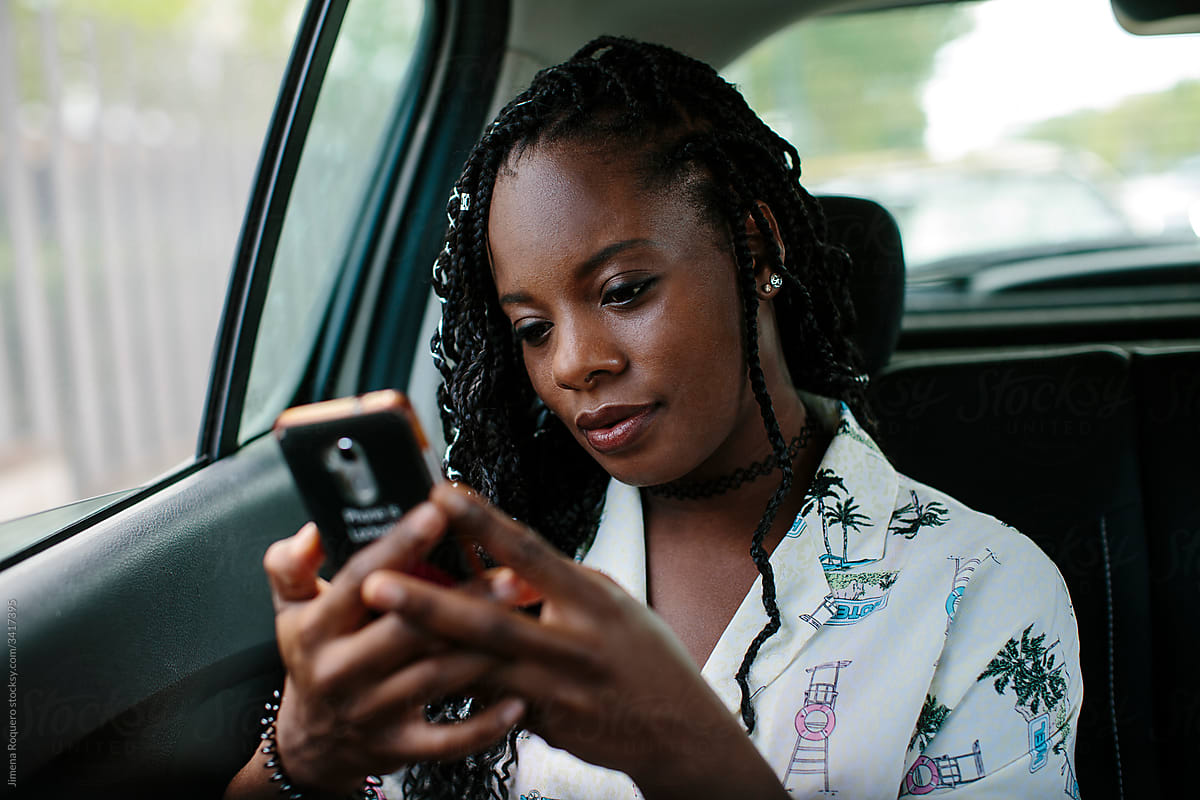Young attractive woman inside a car texting on her smart phone