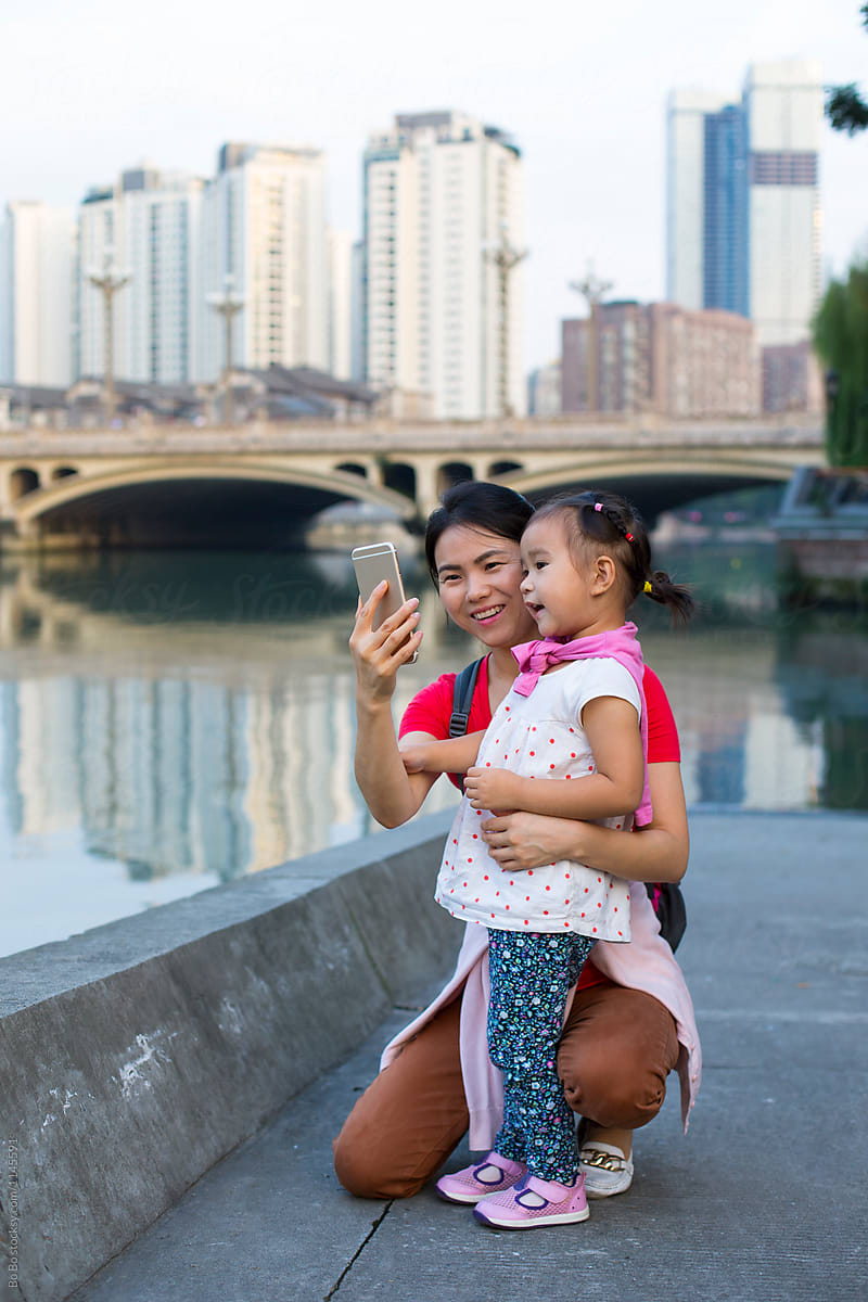 little asian girl using mobile phone talking picture with her mother