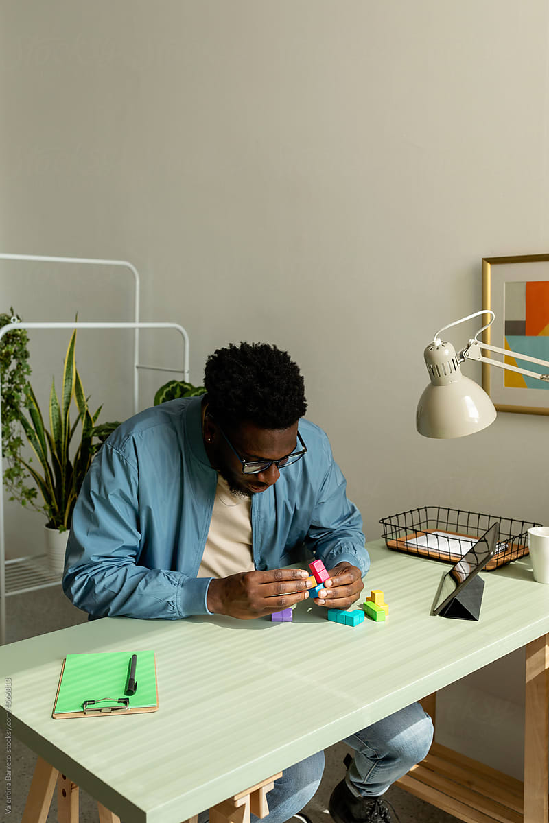 Black man making wooden geometric puzzle in office
