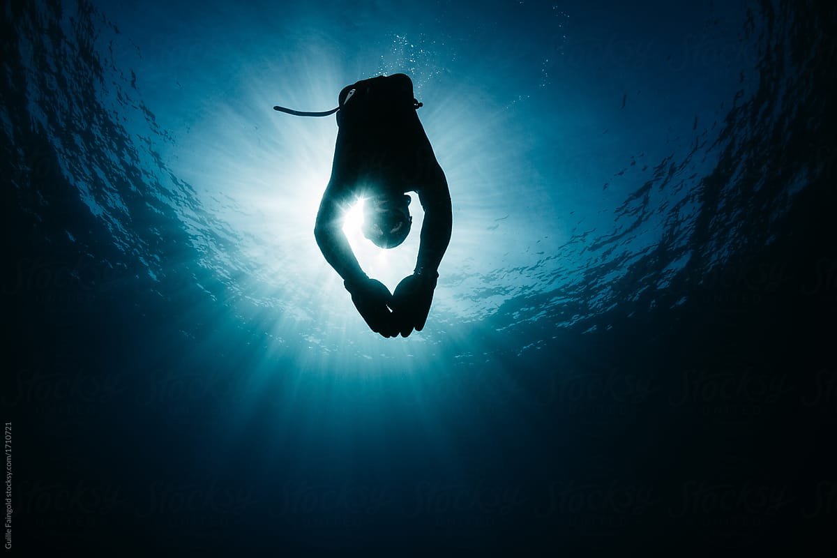 Diver swimming underwater in bright sunlight