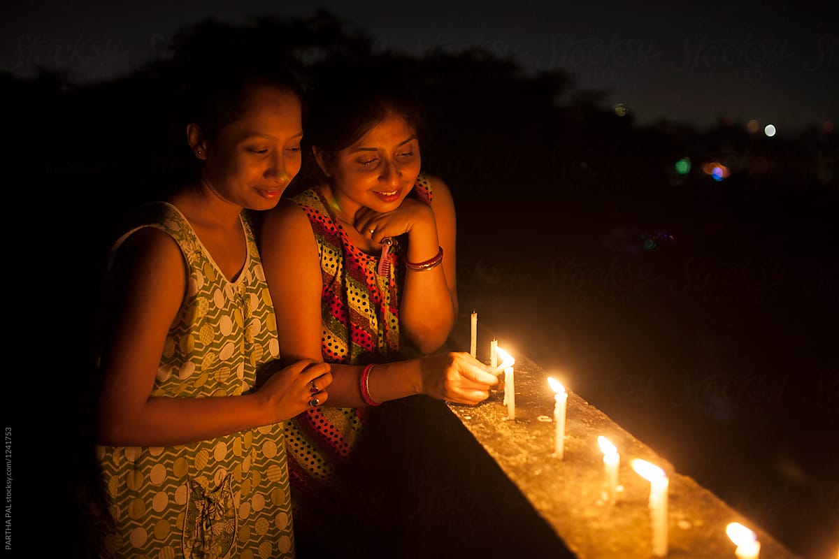 Two young woman lighing candle at night in outdoor