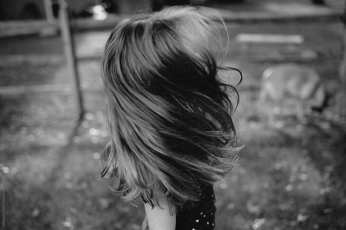 Girl swinging hair outdoors in black and white.