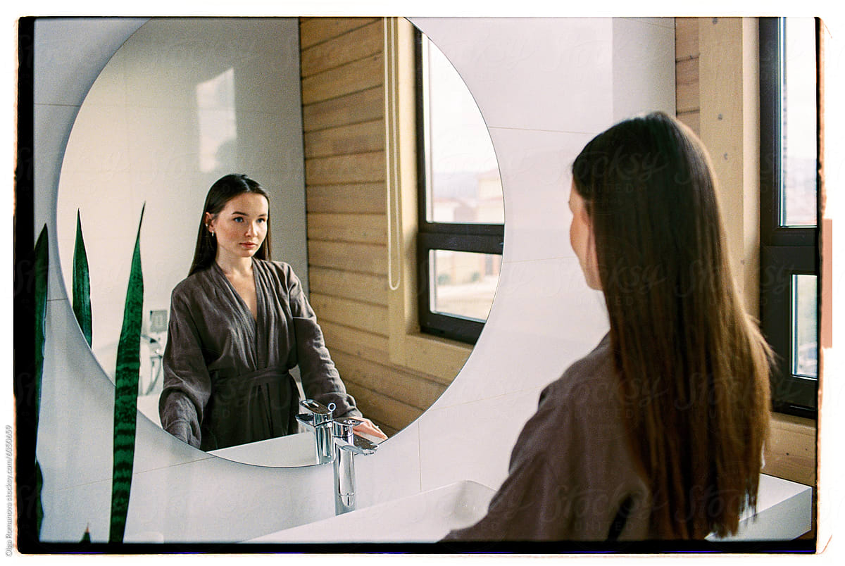 Attractive woman in bathrobe looking at her reflection in a bathroom