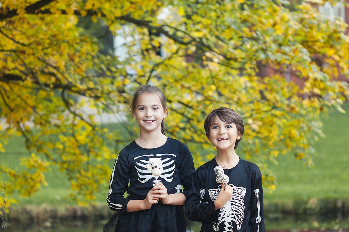 Funny kids in skeleton costumes with halloween candy