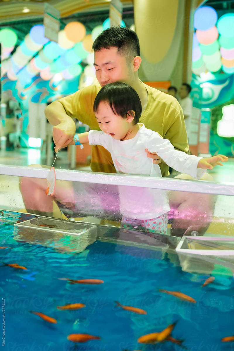 Asian Father And Daughter Fishing For Goldfish by Stocksy Contributor  Rein Cheng - Stocksy