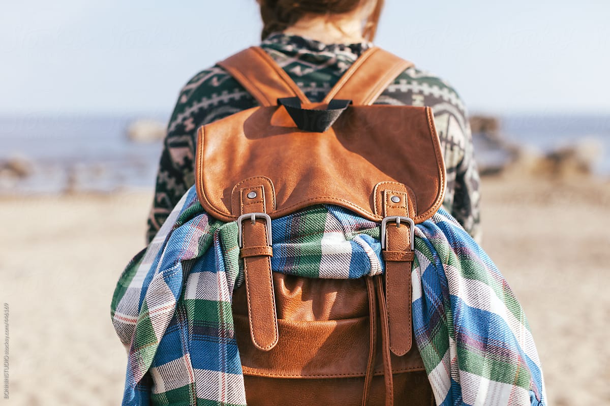 Traveler woman with leather backpack outdoors.
