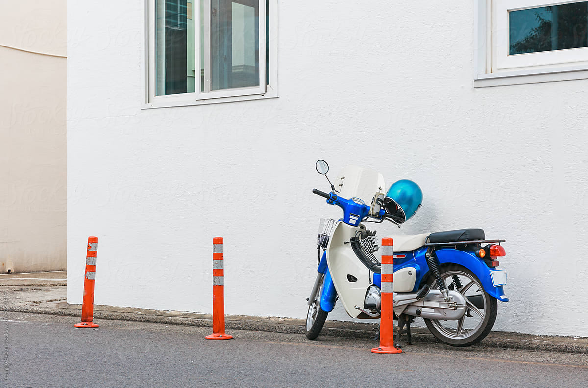 Close-up of a blue scooter parked next to a building.