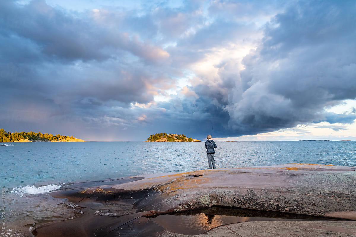Boy Fishing with Dark Storm Clouds on Sea Kayak Camping Trip to Georgian Bay Killarney Ontario Canada