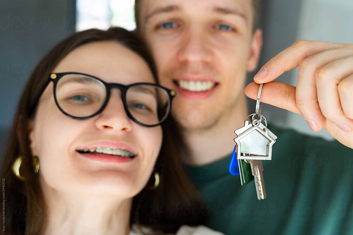 Happy millennial couple selfie holding key from a new home/apartment