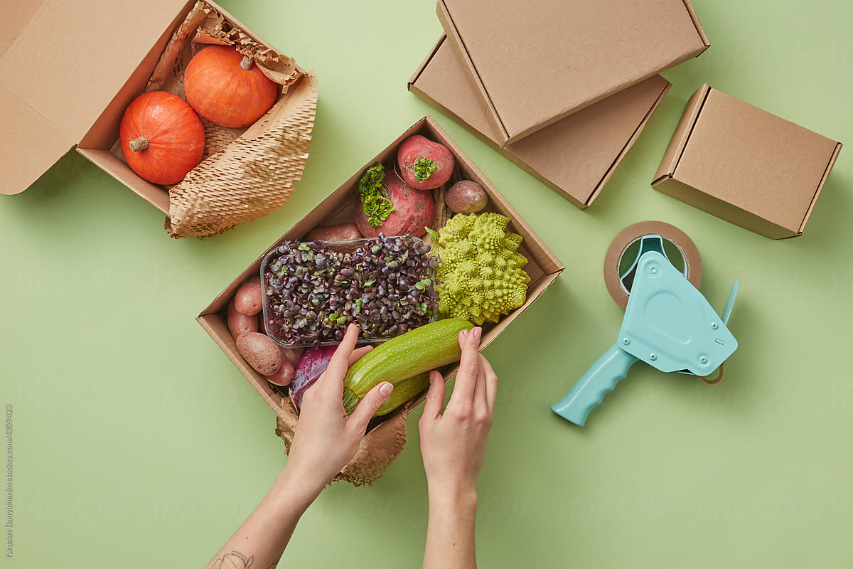 Woman packing vegetables in box for delivery