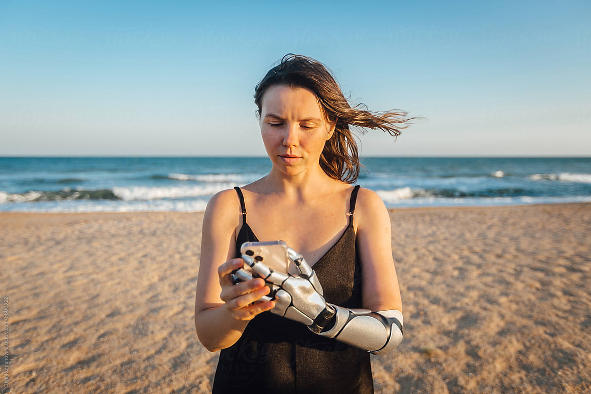 Woman with arm prosthesis looking at the screen of her phone