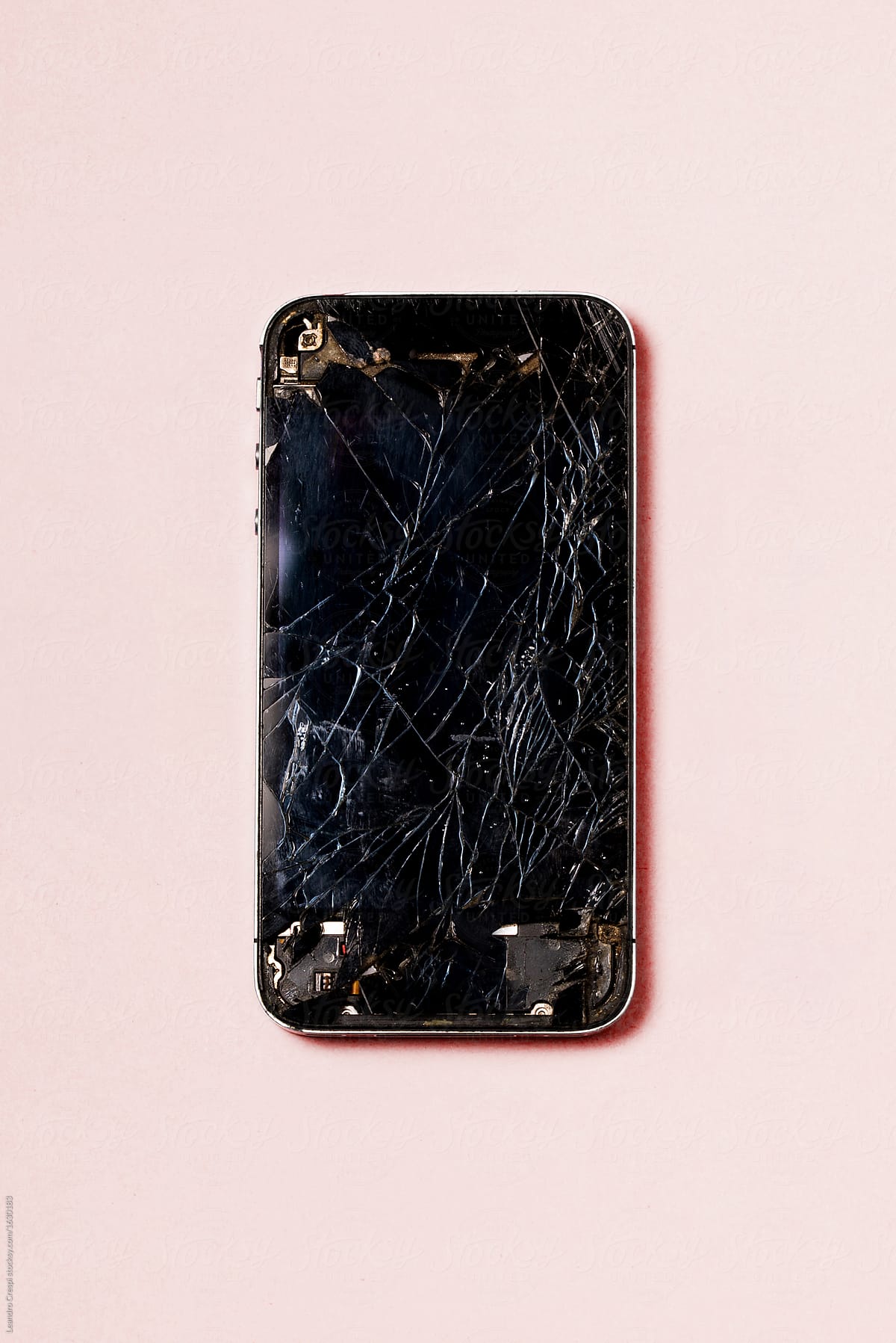 Smartphone with cracked screen over pink background