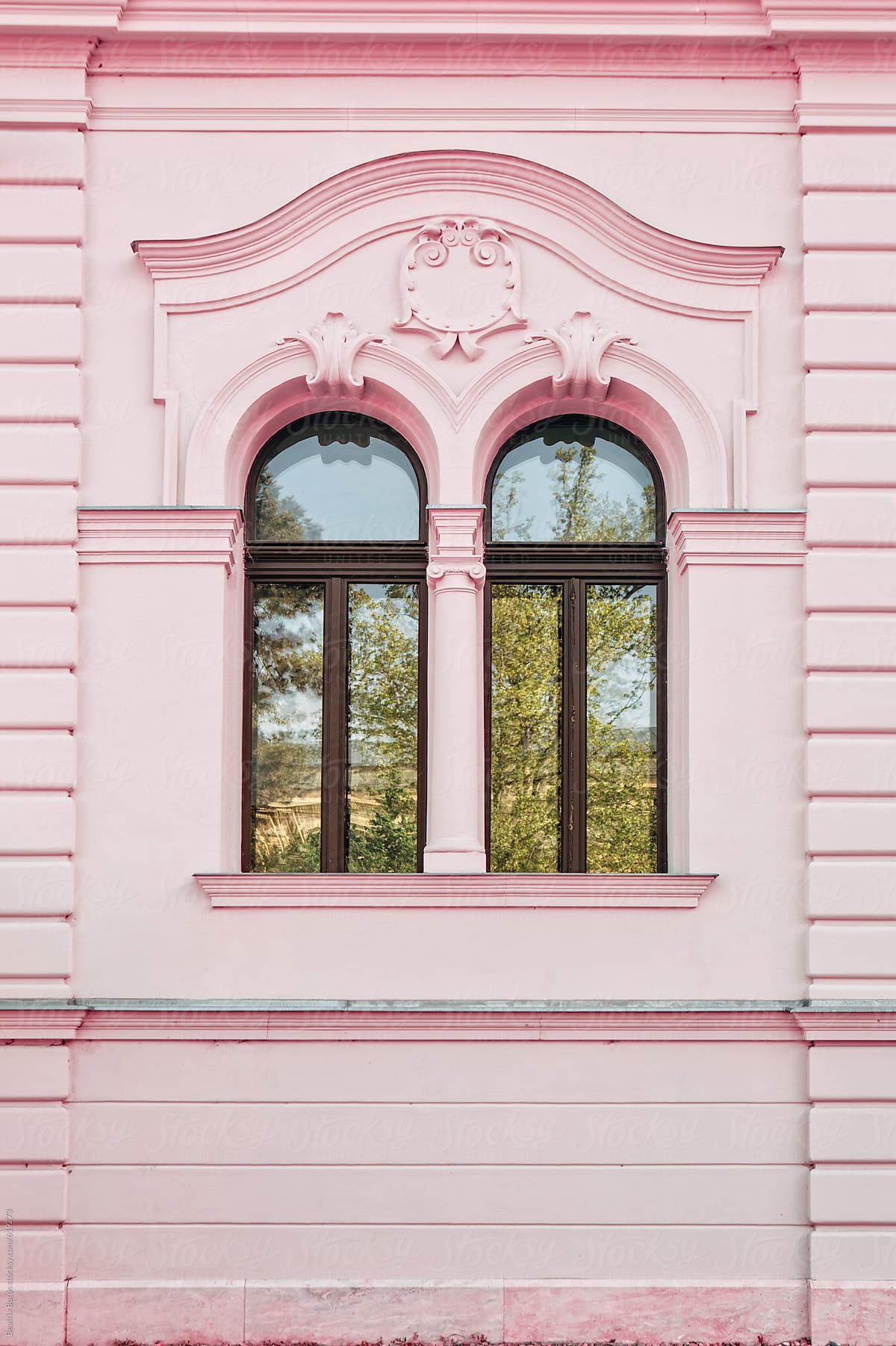 Wall of a pink building with two twin windows