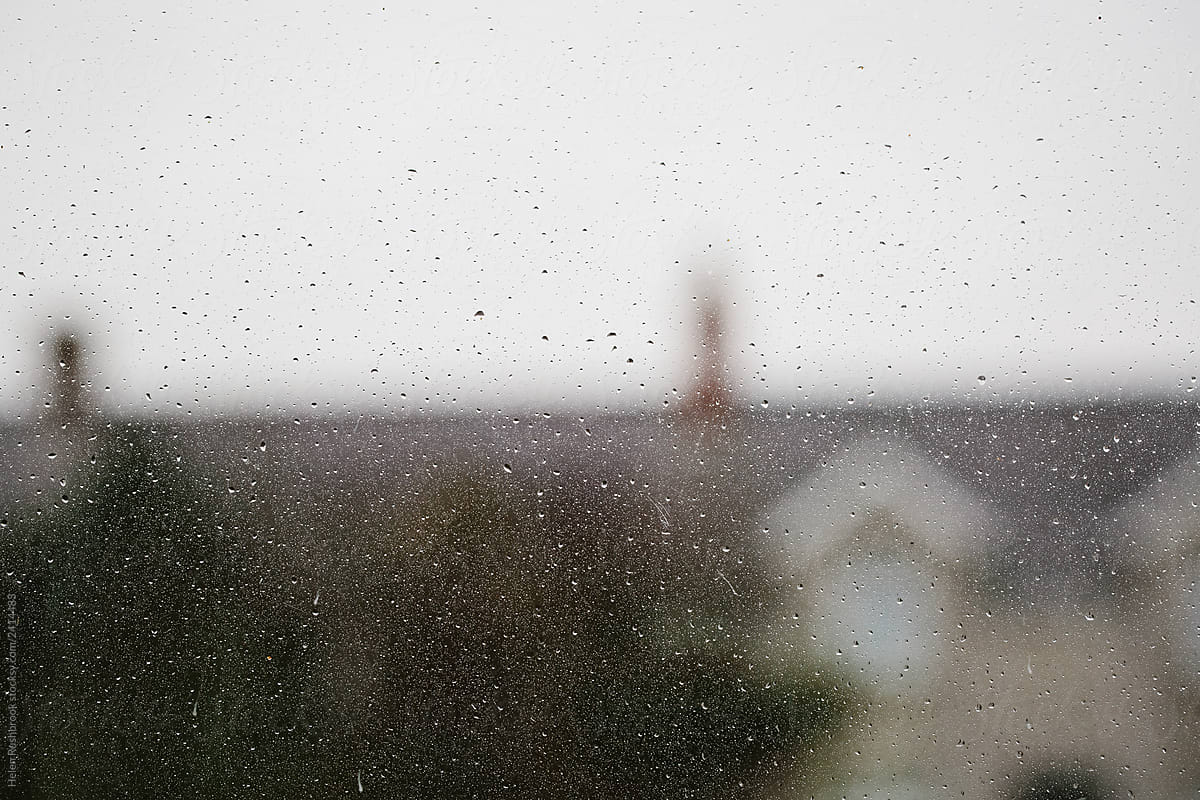 A rainy window with blurry rooftops and chimney pots. The UK.