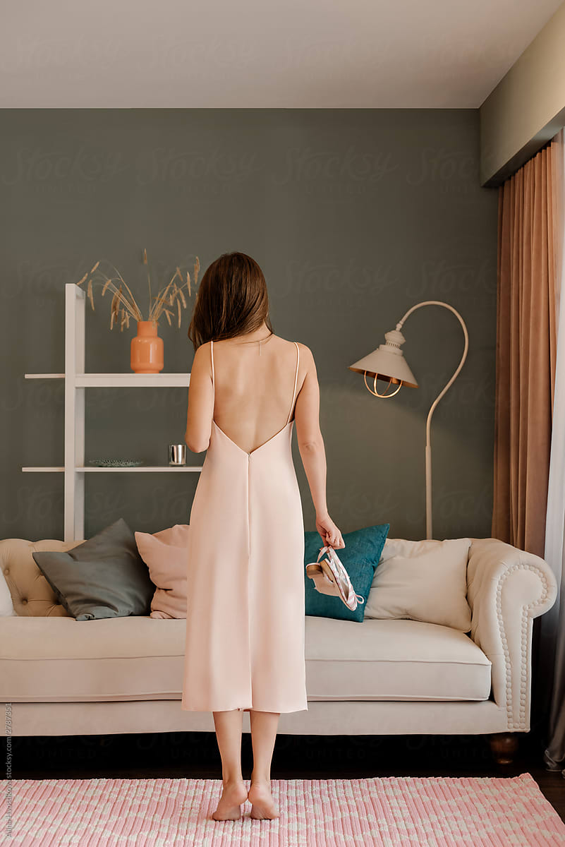 Unrecognizable woman in dress standing near couch