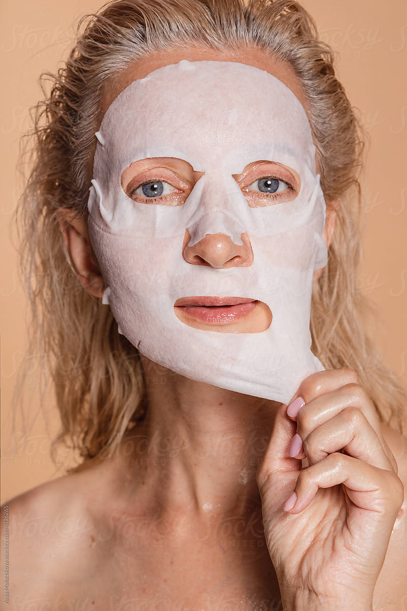 Middle aged woman pulls off a moisturizing mask from her face