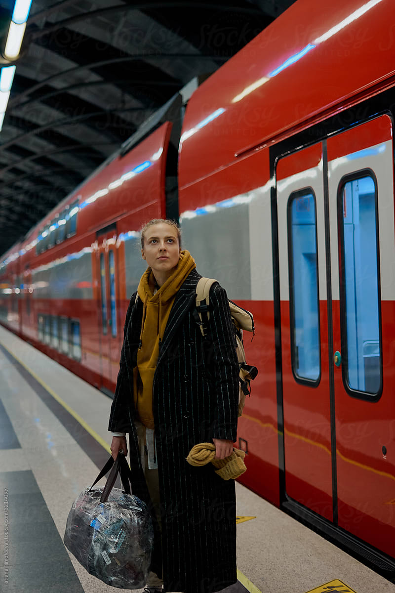 woman stands on an empty platform and waits for a high-speed train.