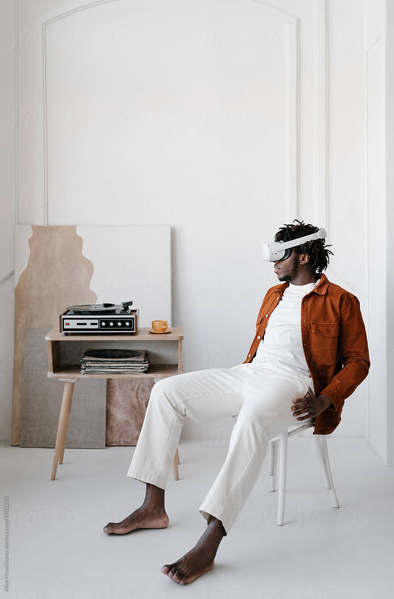 Black man with VR headset sitting near turntable