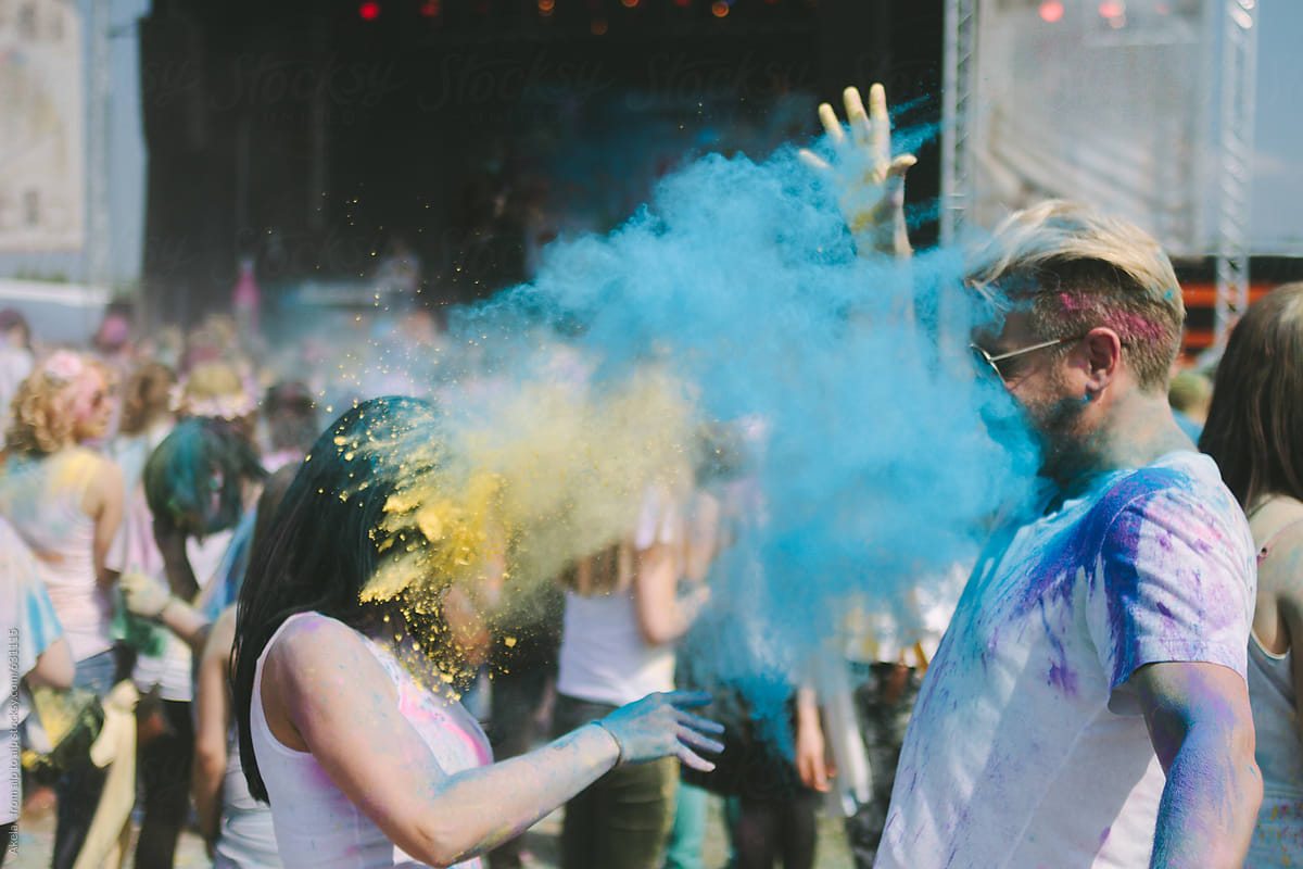 young couple throwing colorful powder on each other at an outdoor color festival