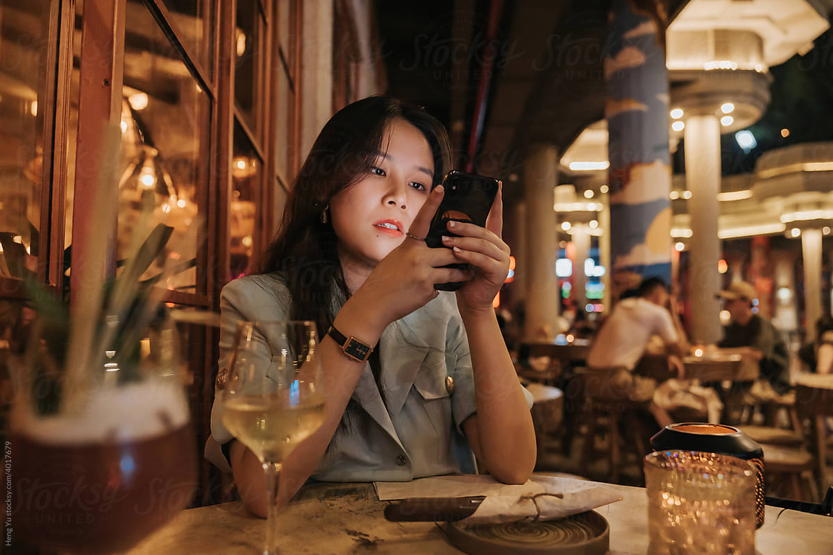 Asian woman using her phone in a bar