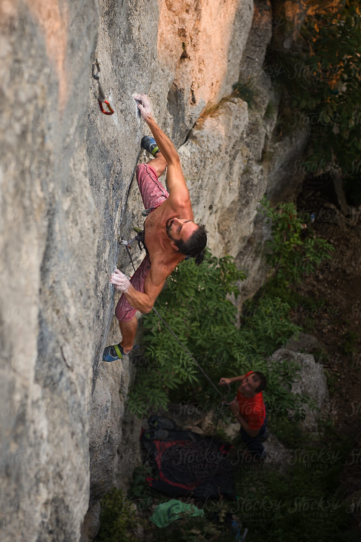 Strong man rock climbing a hard route outdoor at sunset