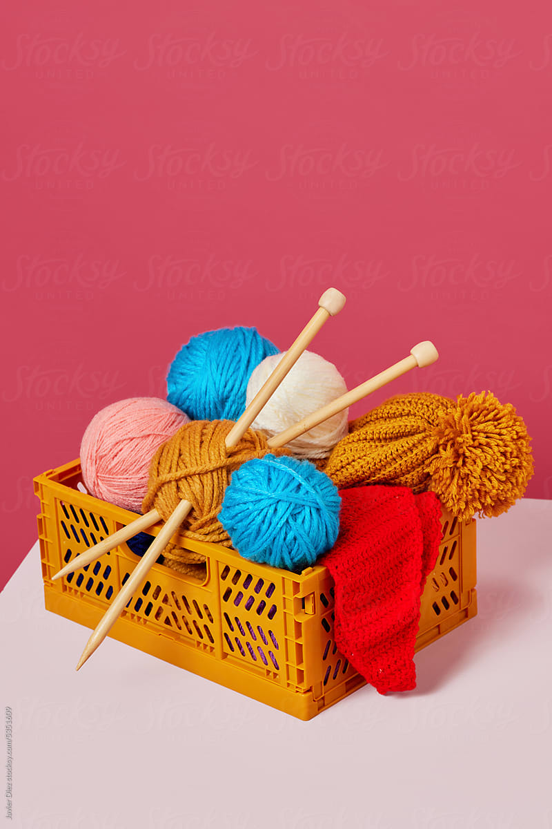 Clews of yarns with needles in basket on desk
