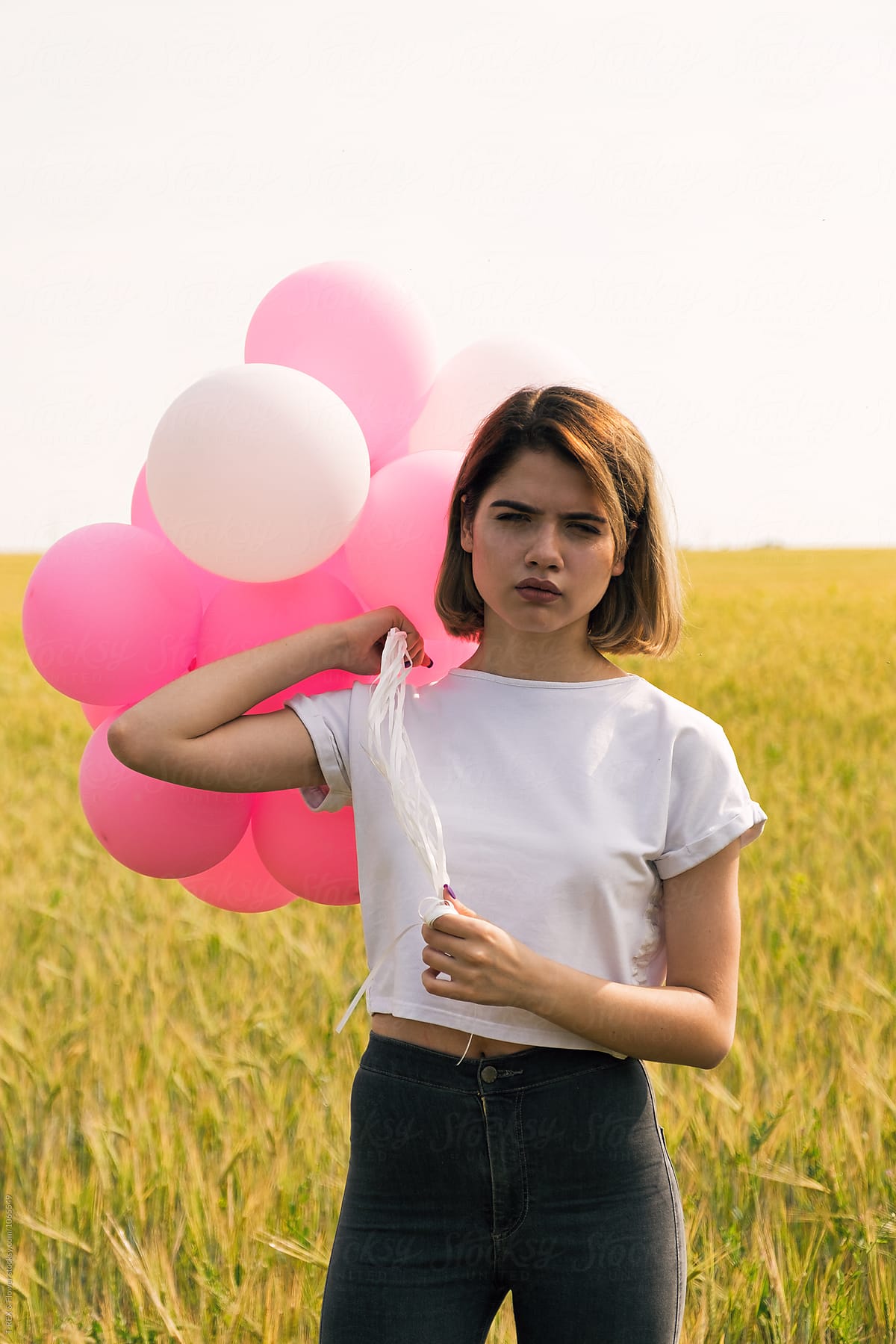 Serious Teen Girl With Balloons Looking At Camera By Stocksy