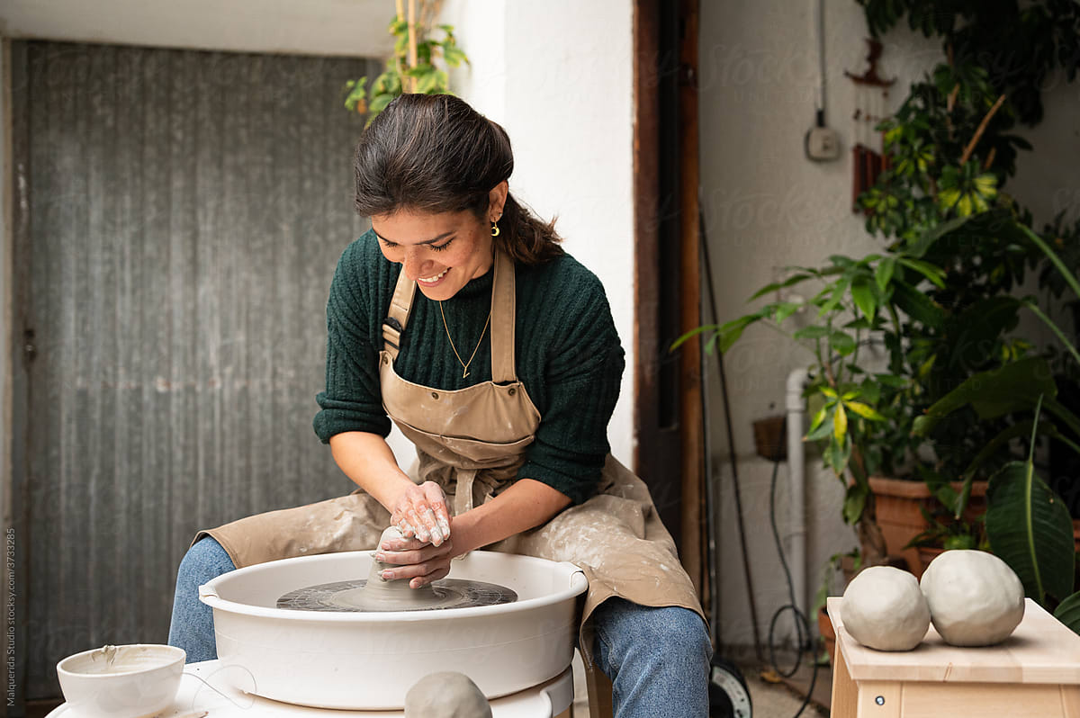 Smiling ceramist makes clayware in a Pottery lathe