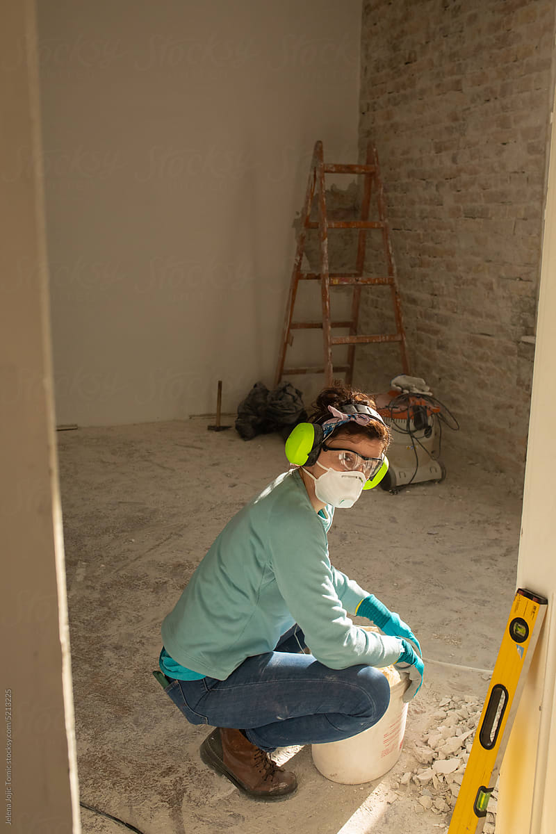 A tired woman is renovating her home, looking at the camera